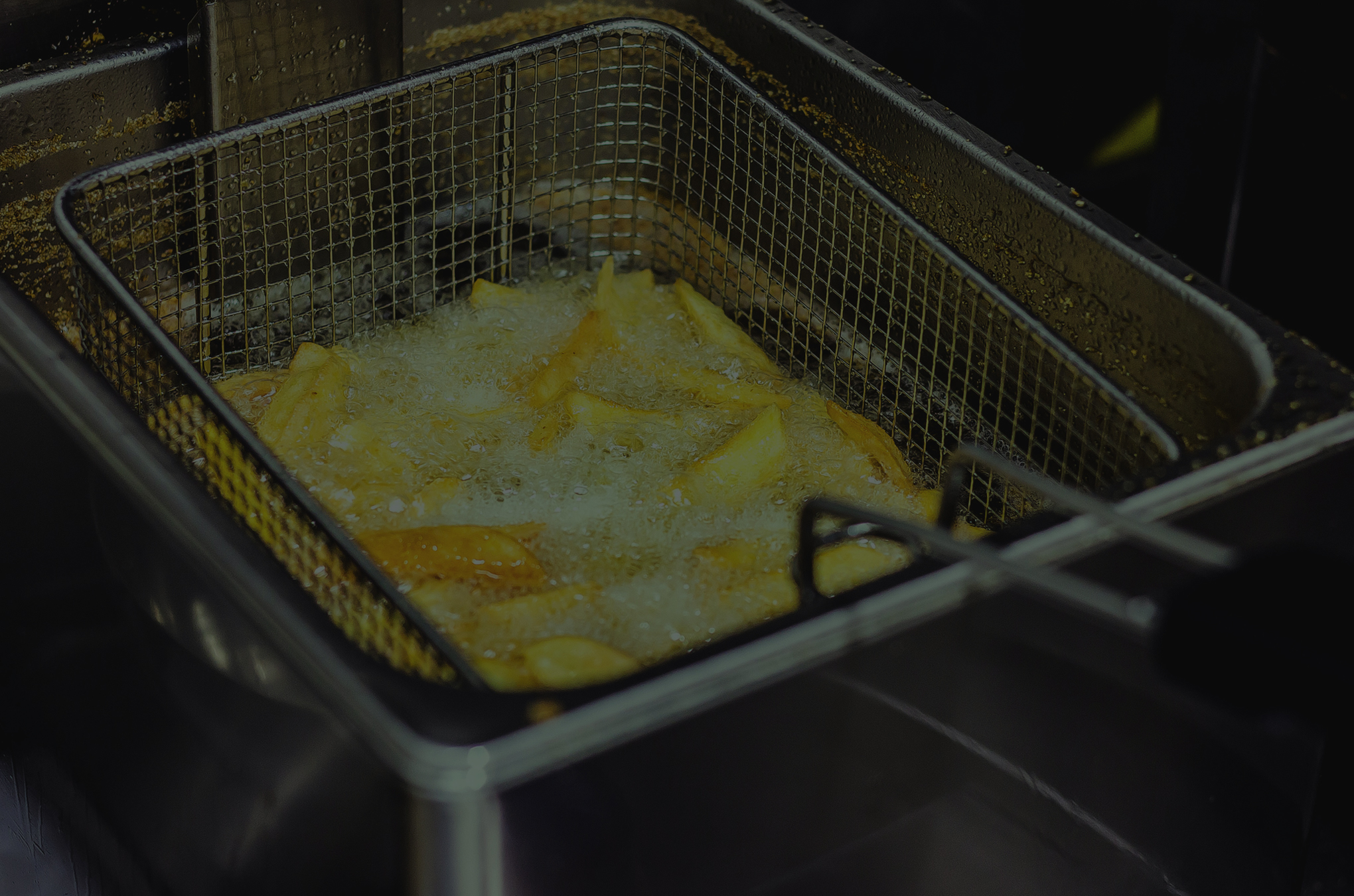 Darkened French fries being fried in oil
